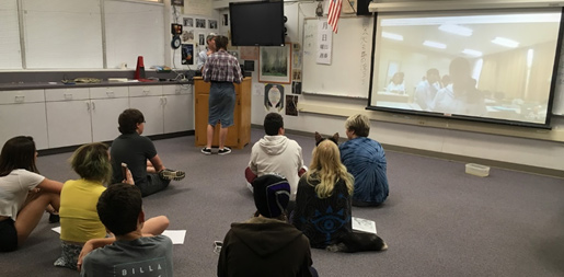 Students wait their turn to practice identifying fruit and animals in Japanese.